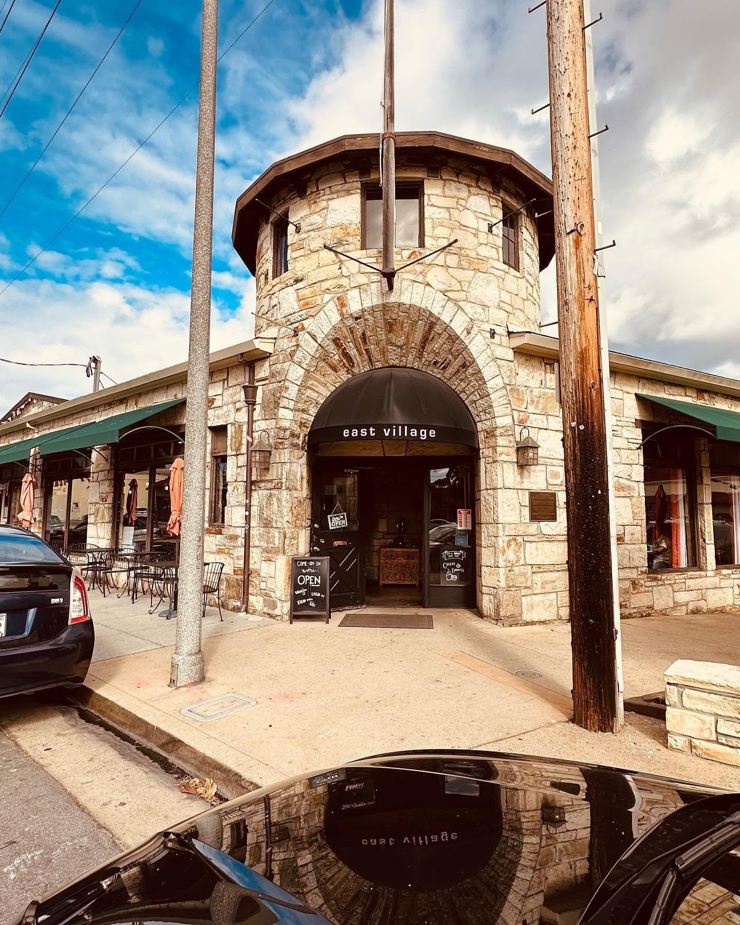 The Carmel-stone turret entrance of East Village Cafe with its black awning